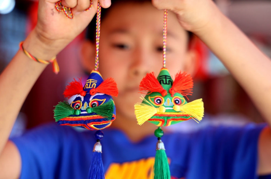 6月22日,在山东省滨州市无棣县古城风景区,小朋友展示选购的香囊。新华社发(初宝瑞 摄)