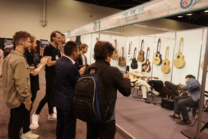4月13日，在美国加利福尼亚州阿纳海姆会展中心，参观者在中国贵州正安吉他产业园一家公司展位观看乐器表演。