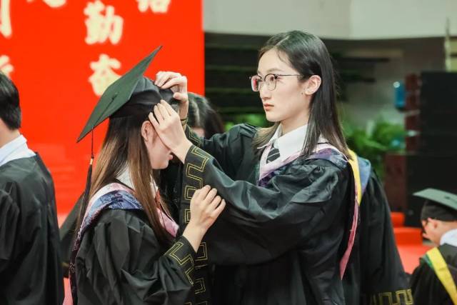 广东工业大学毕业生互相整理学位帽。