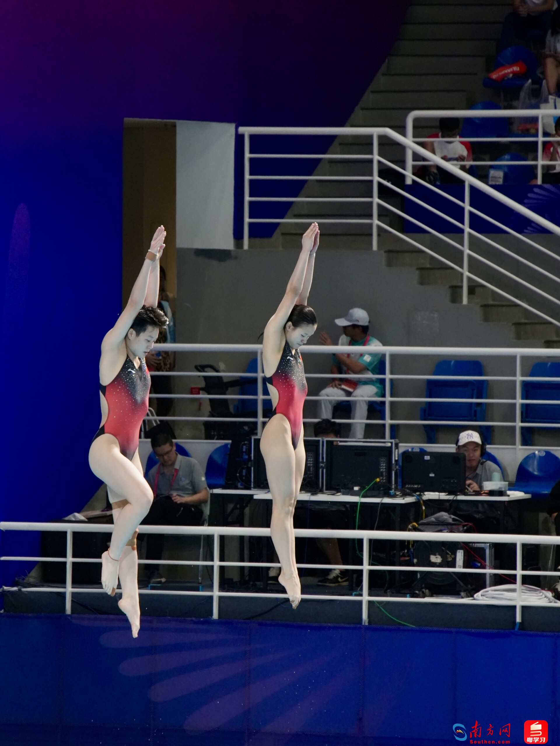 比赛中,陈艺文(左)与林珊(右)跃起时紧盯下方水面。