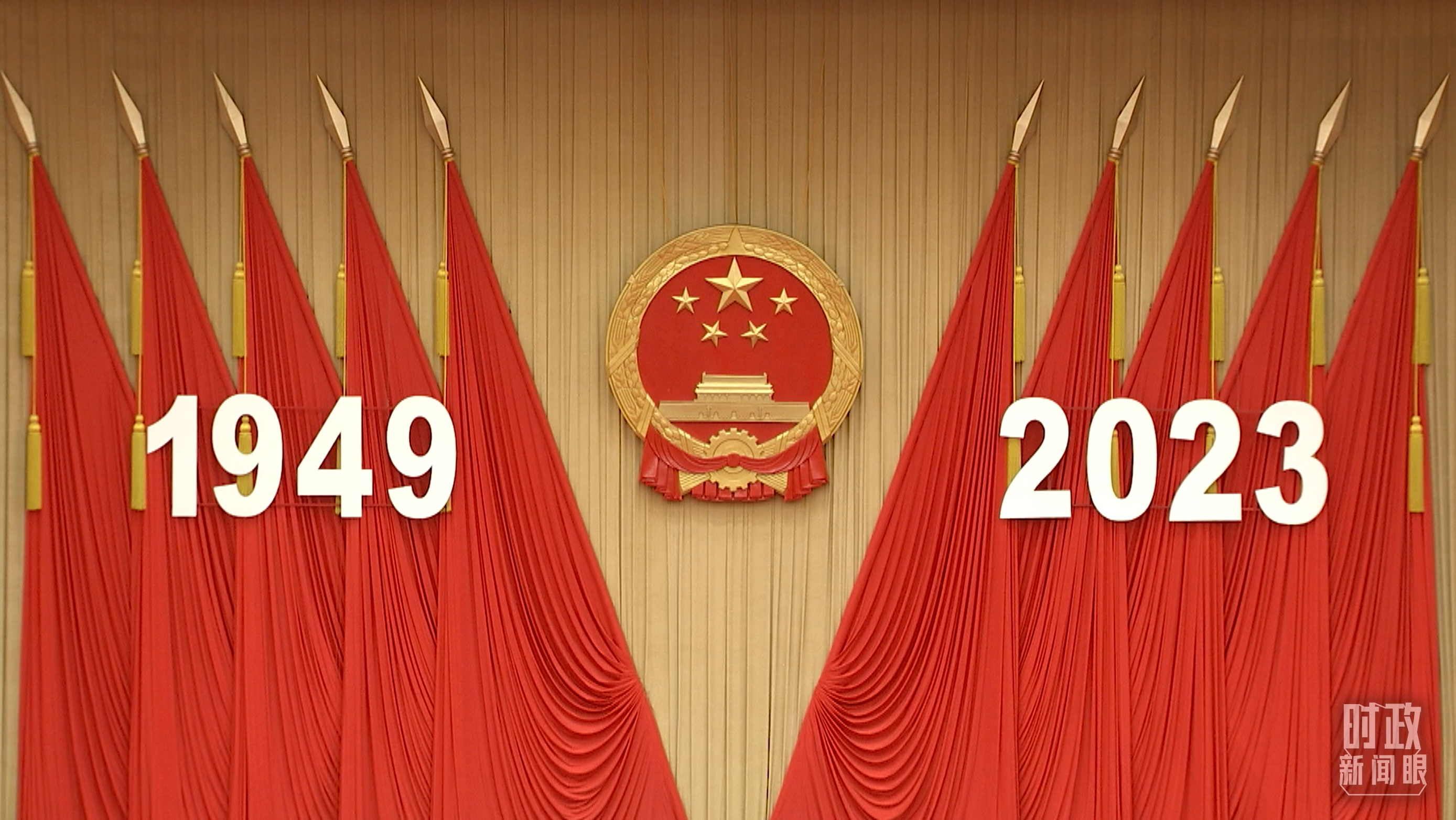 人民大会堂宴会厅内，主席台上方高悬着庄严的国徽，“1949－2023”大字年号在鲜艳的红旗映衬下格外醒目。
