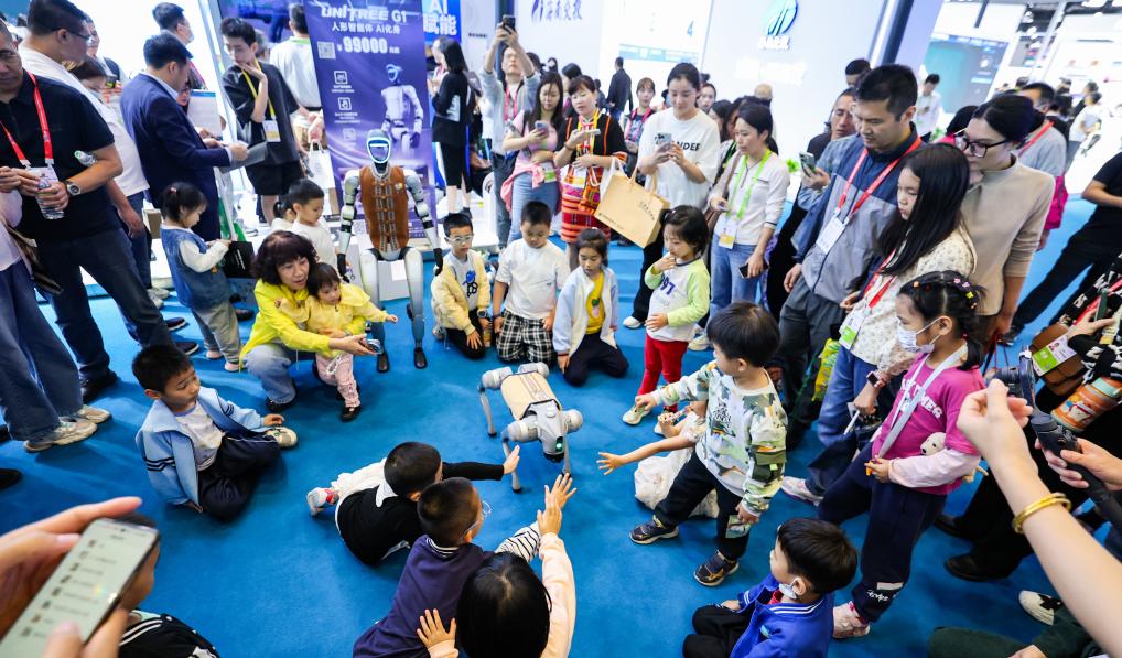 4月13日，在第五届消博会现场，小朋友和宇树科技展示的机器狗互动。新华社记者 杨冠宇 摄