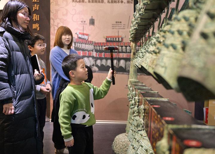 △2026年1月3日,小游客在中国考古博物馆互动展区参加仿古编钟的敲击体验活动。