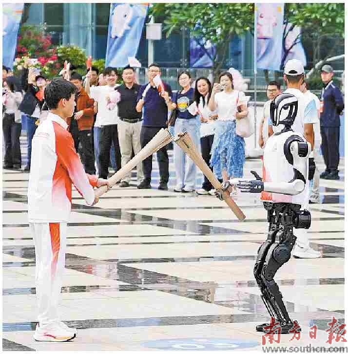 “0号”火炬手人形机器人“夸父”向“手搓火箭”的高中生王裕宁传递火炬。    南方日报记者 张令 姚志豪 钟志辉    张迪 郑新洽 朱洪波 摄