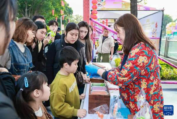 1月26日，广州非遗市集上，香港吹糖人师傅薛锦屏在指导小朋友吹糖人。（受访单位供图）