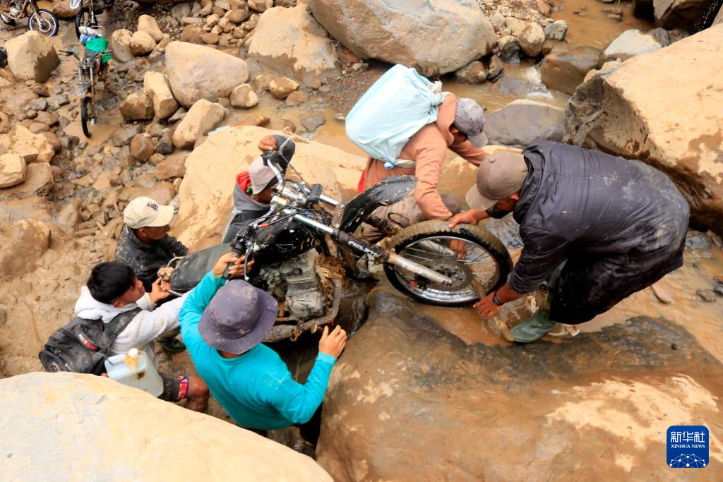 12月9日,在印度尼西亚亚齐省,人们带着摩托车过河。新华社发(尤哈姆摄)