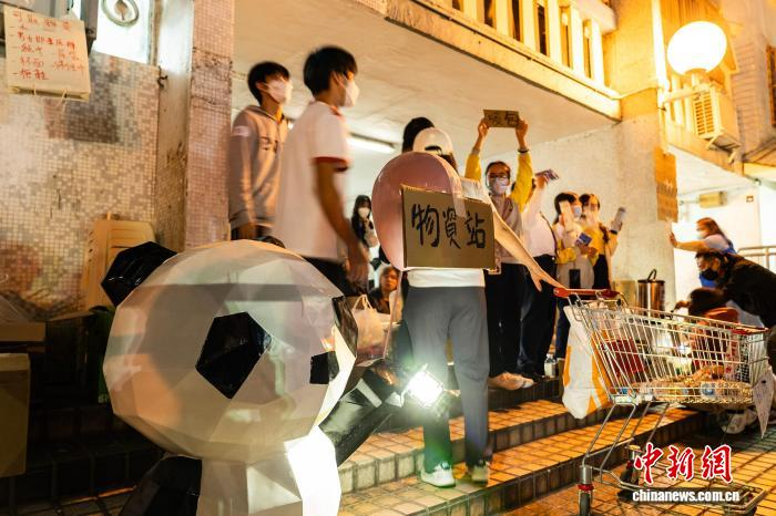 11月27日晚,在香港大埔宏福苑火灾现场附近的广福邨公众活动平台一角,青少年参与为火灾受影响市民提供热水、暖包等物资帮助。图为青少年在简易的“物资站”为有需要者提供物资帮助。 中新社记者 侯宇 摄