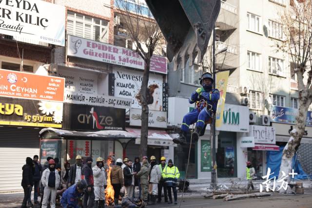 伊南努街上，中国蓝天搜救队员“乘坐”土耳其挖机向废墟飞去。