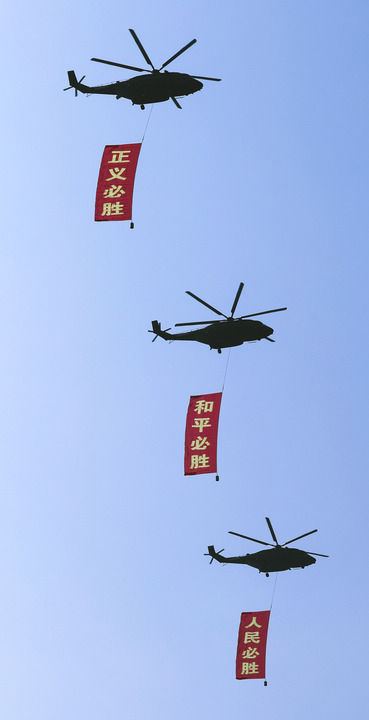2025年9月3日，纪念中国人民抗日战争暨世界反法西斯战争胜利80周年大会在北京隆重举行。这是空中护旗梯队通过天安门广场，3架直-8L运输直升机分别悬挂“正义必胜”“和平必胜”“人民必胜”条幅。新华社记者 李钢 摄