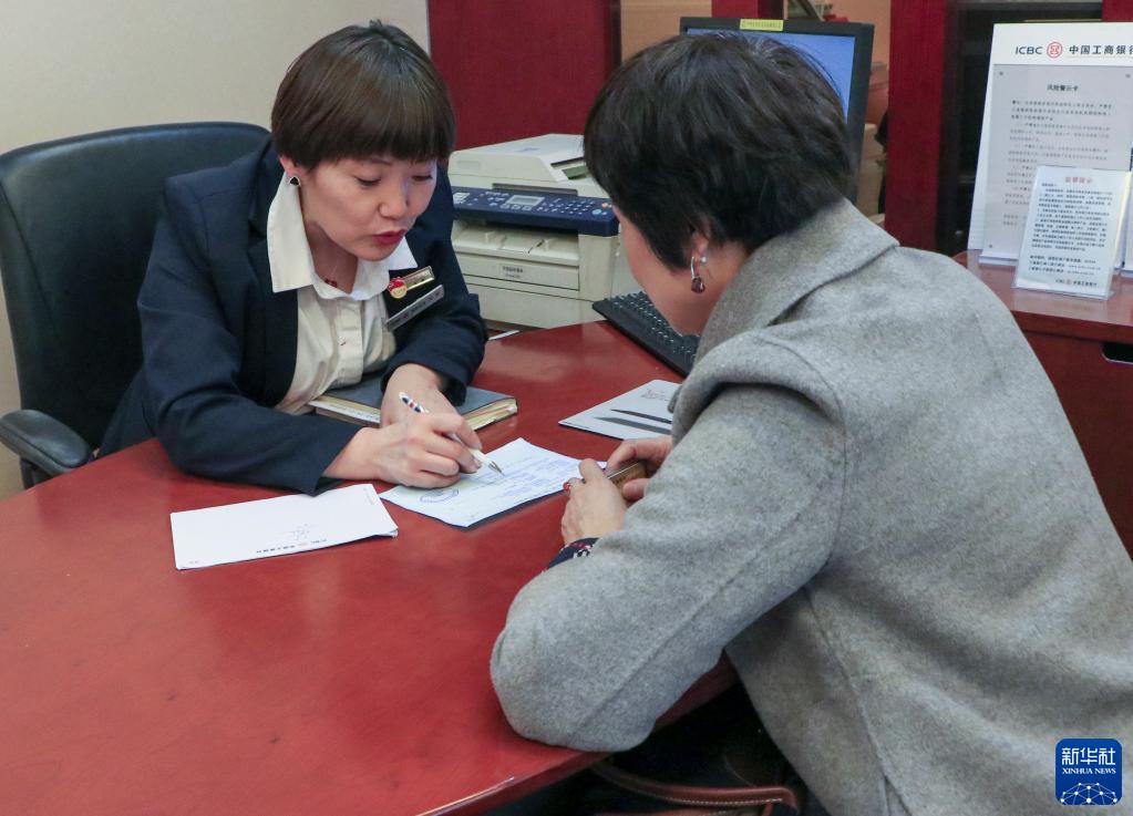 在中国工商银行新疆乌鲁木齐的一处营业网点，李鹏（左）为客户解答问题（2018年11月摄）。新华社发