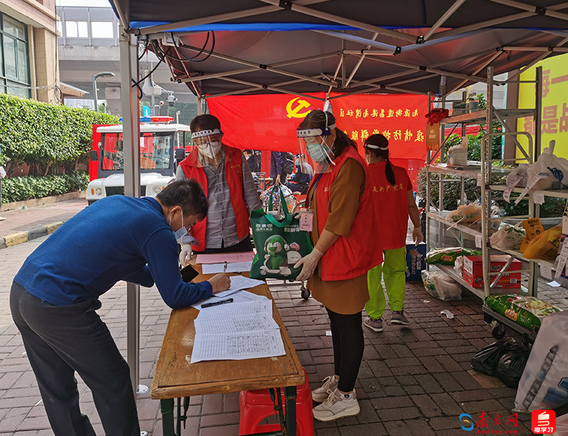 在荔港南湾另外一个出入口，身穿红马甲的志愿者在协助居民拿物资。