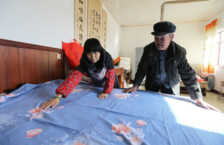 甘肃省定西市安定区内官营镇先锋村村民在整理刚领到的新床单（2025年11月19日摄）。初冬时节，当地开展“问暖”“送暖”“助暖”活动，保障困难群众温暖过冬。新华社发（王克贤摄）