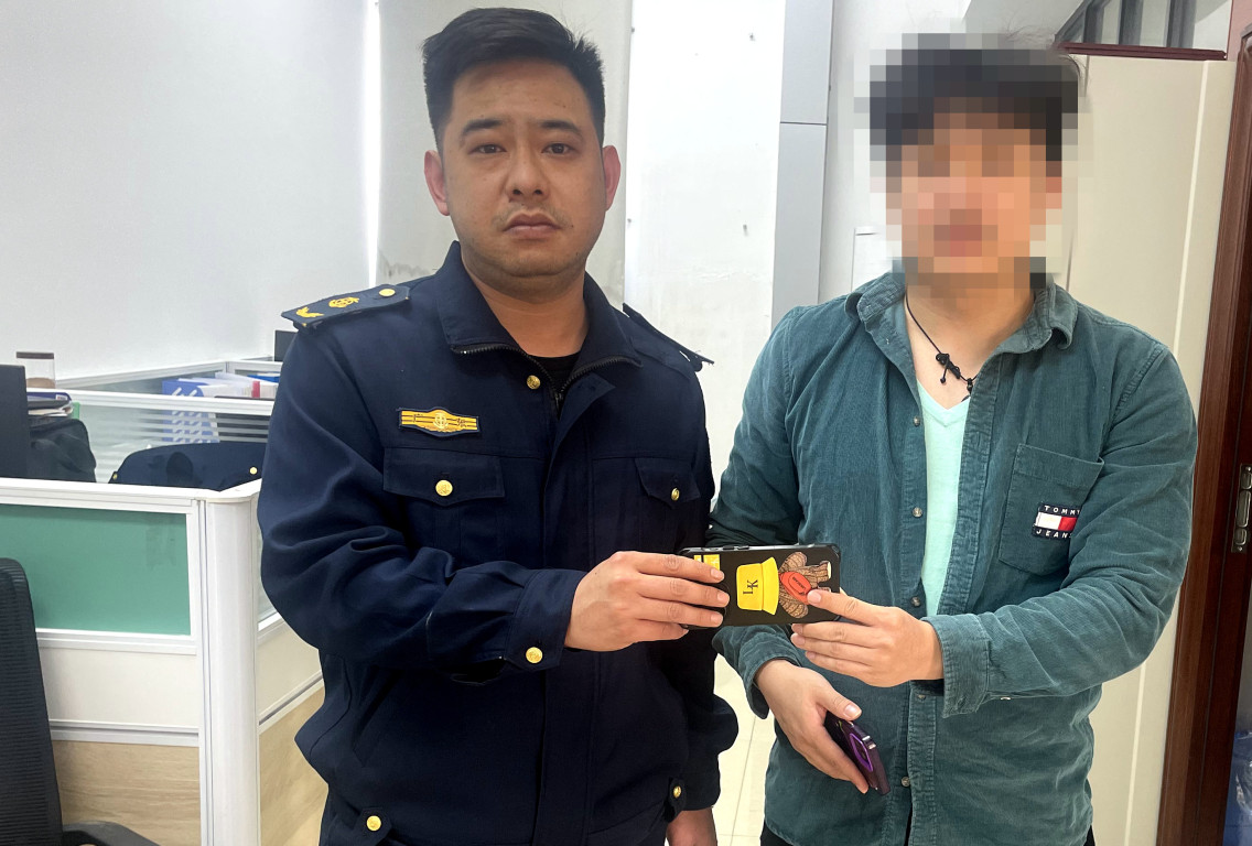在茂名路政中队，失主陈先生（右）从路政员颜文龙手中领回失物手机并致谢