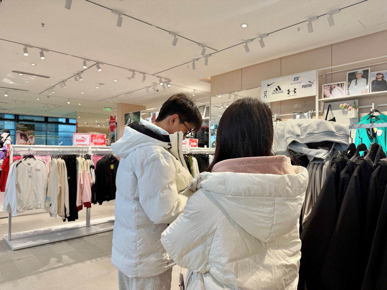 消费者在商场选购羽绒服。